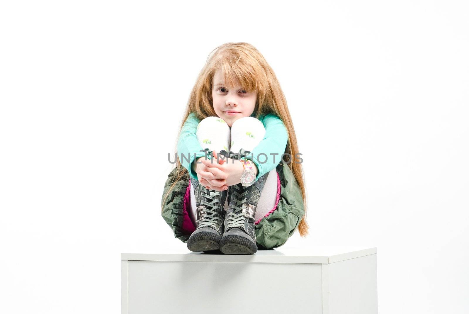 studio shot of pretty little girl sitting on a white cube