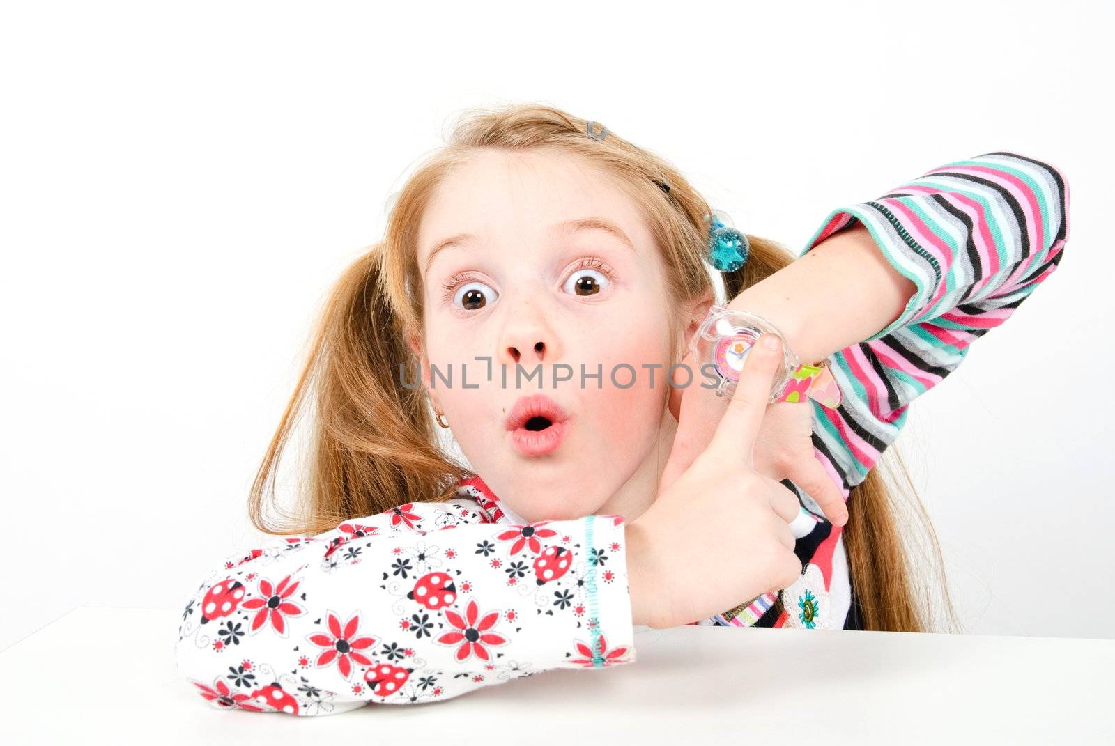 studio shot of pretty little girl pointing at her watch