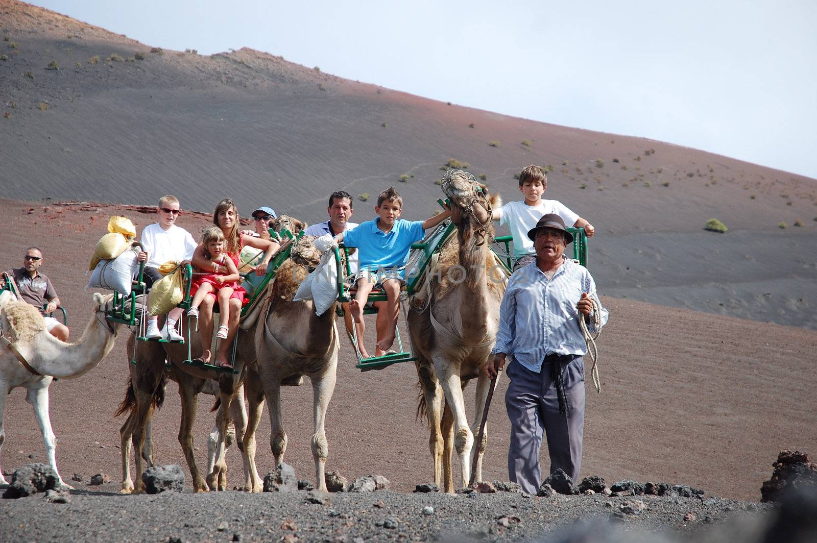 TIMANFAYA NATIONAL PARK, LANZAROTE, SPAIN - JUNE 10: Tourists riding on camels being guided by local people through the famous Timanfaya National Park in June 10, 2009