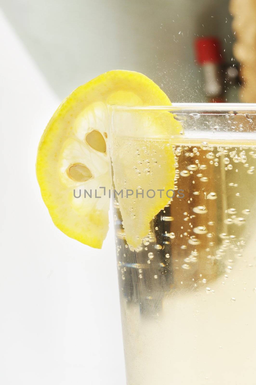 Glass goblet with sparkling lemonade and lemon.
