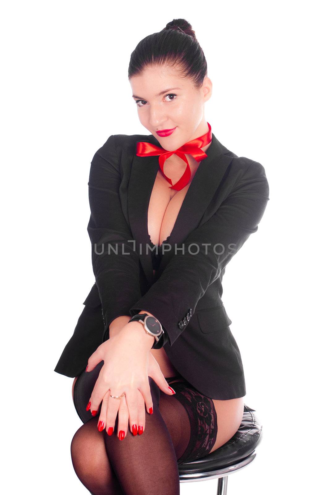 The beautiful sexy girl sits on a bar chair in stockings and a black jacket with a red bow on her neck