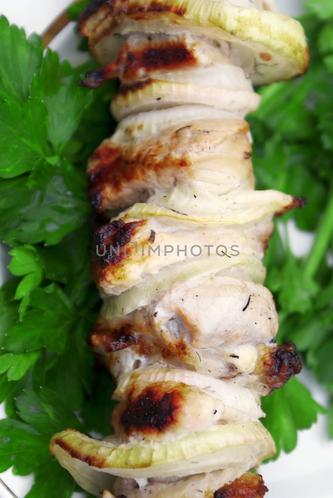 Appetizing juicy shish kebab from fresh pork in green leaves of parsley