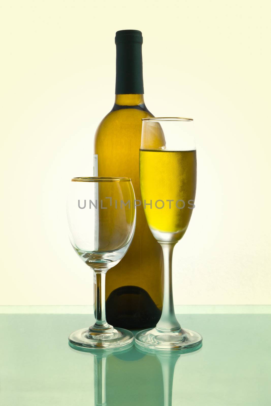 Bottles and glasses of wine on green background