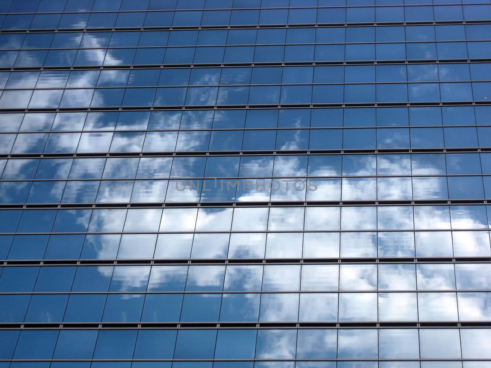 Glass wall with the reflection of blue sky and clouds