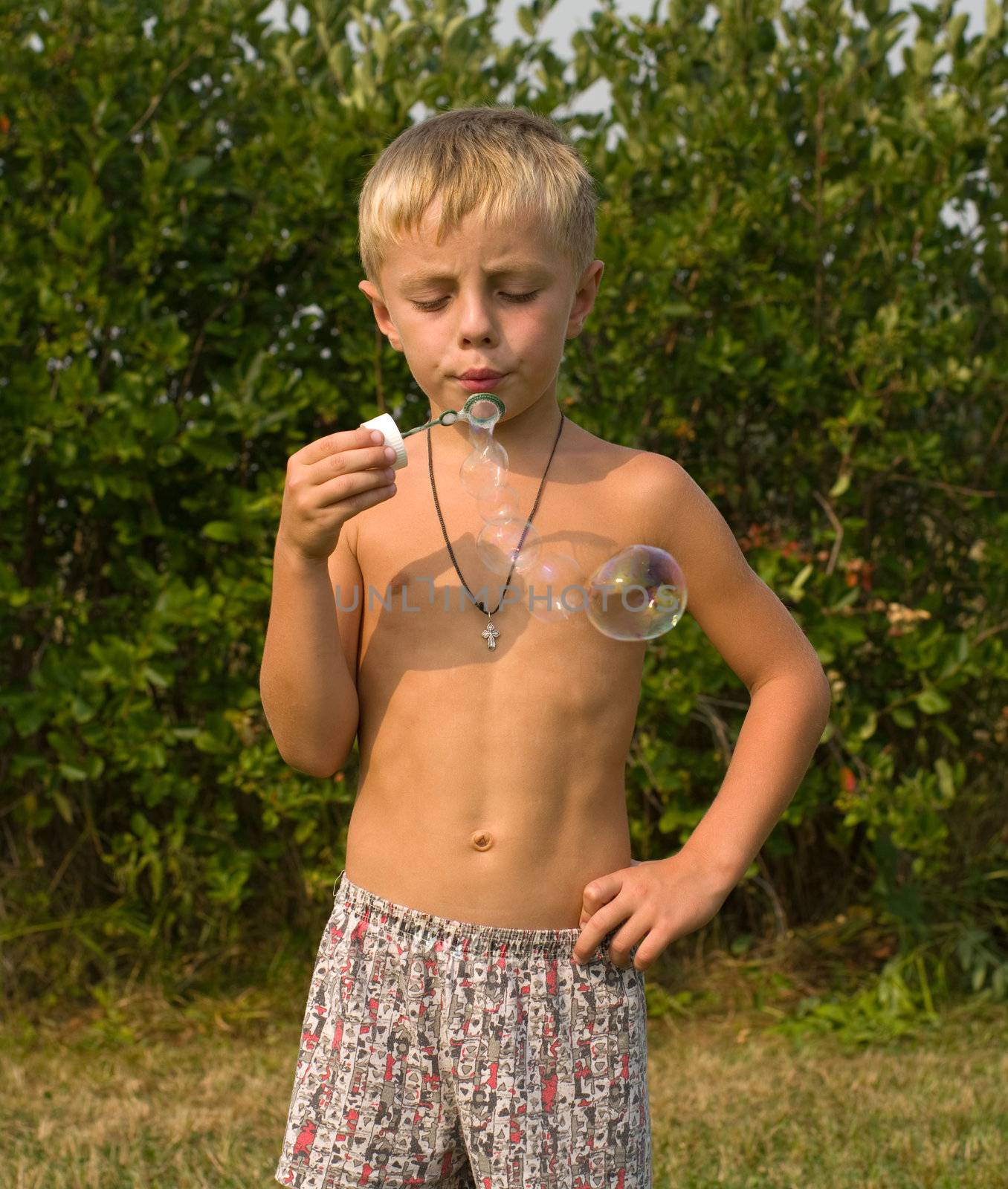 Boy blows bubbles in the garden on a summer day.