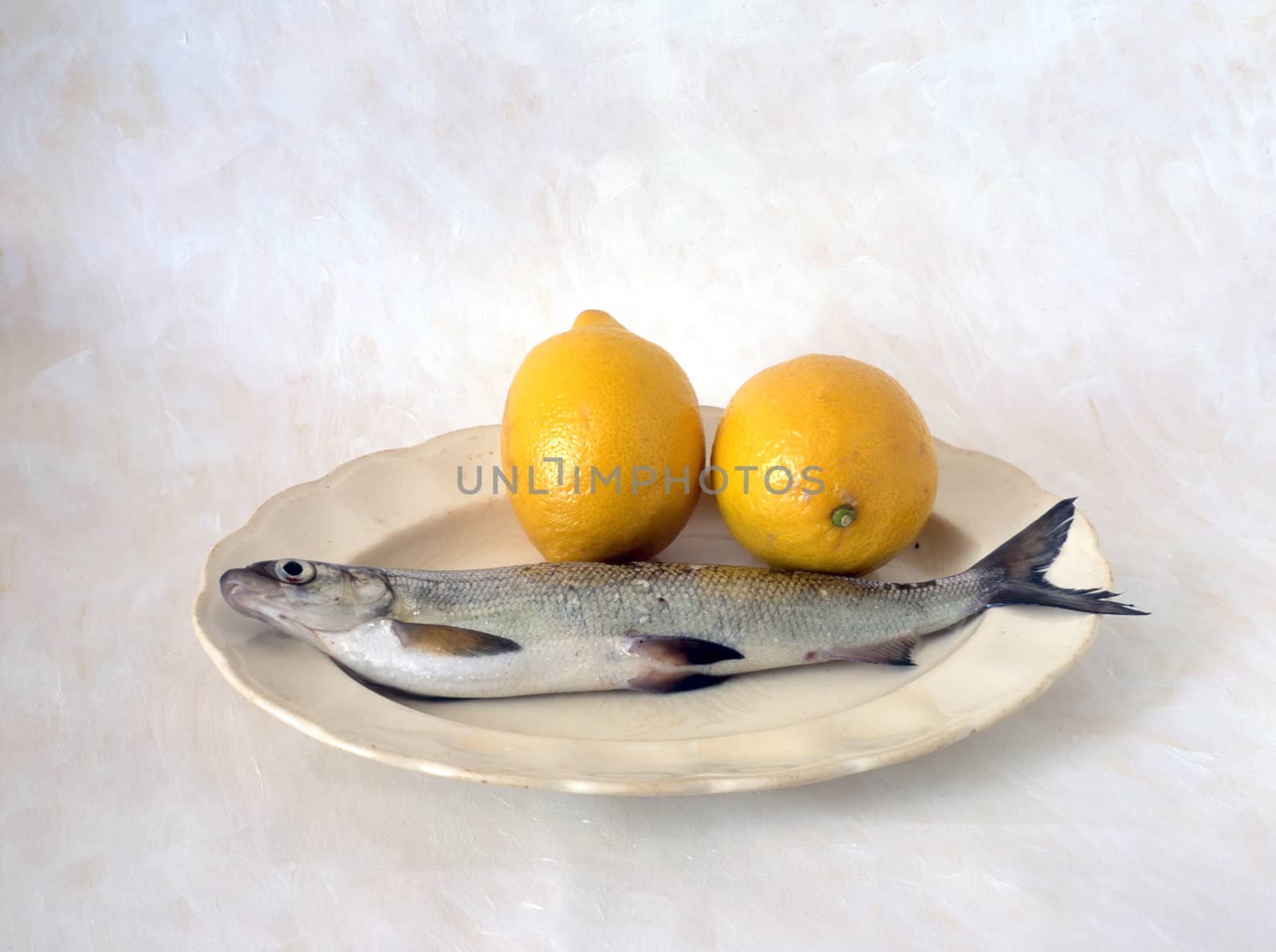 Fish with lemon on plate isolated on painted background