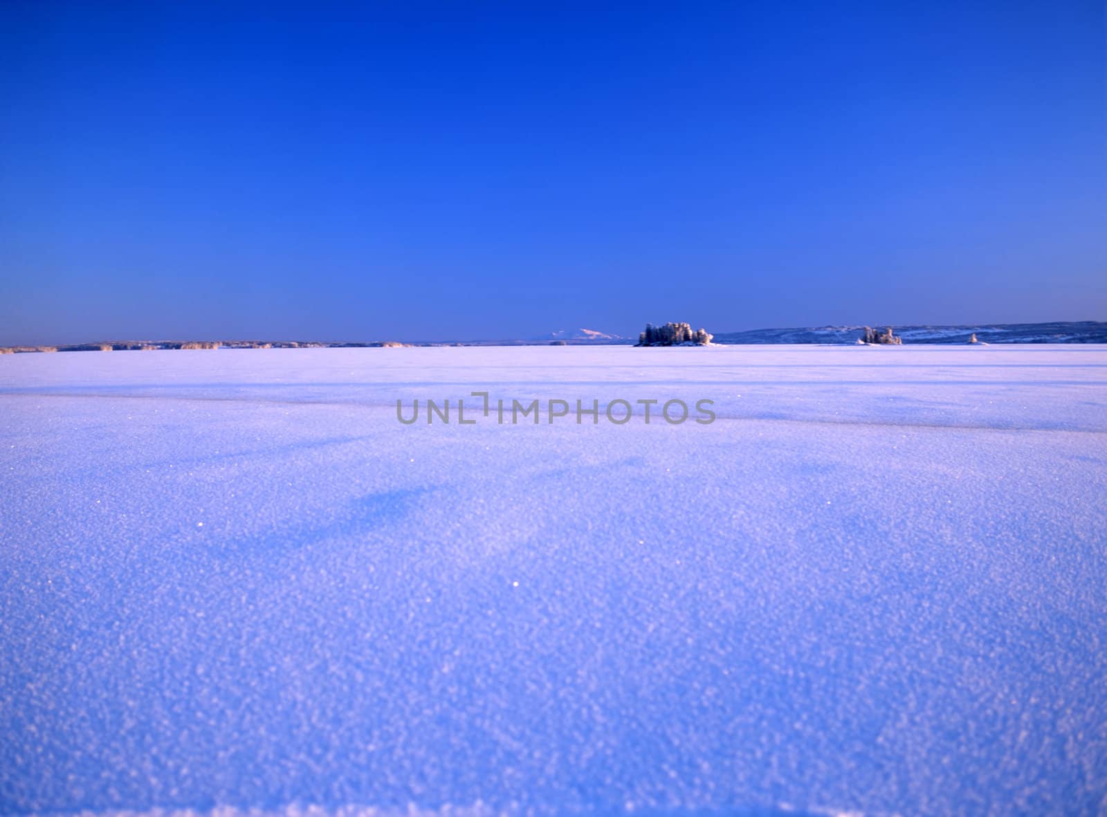 Landscape image of a snowy meadow and blue sky