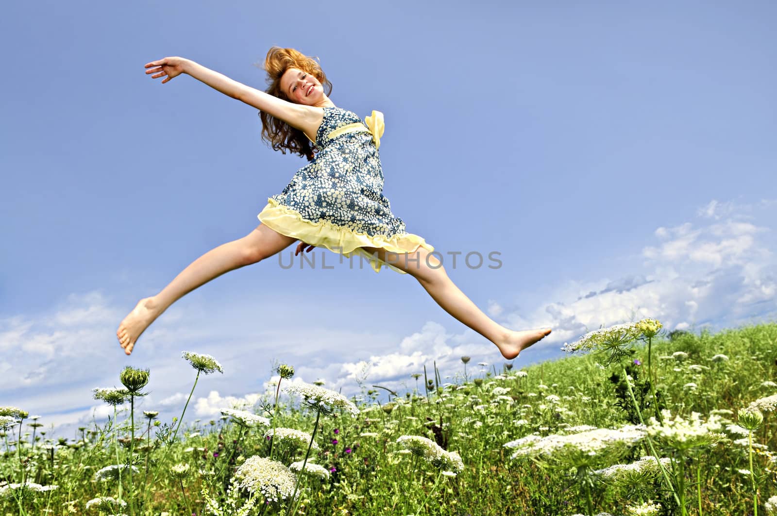 Young girl jumping in meadow by elenathewise