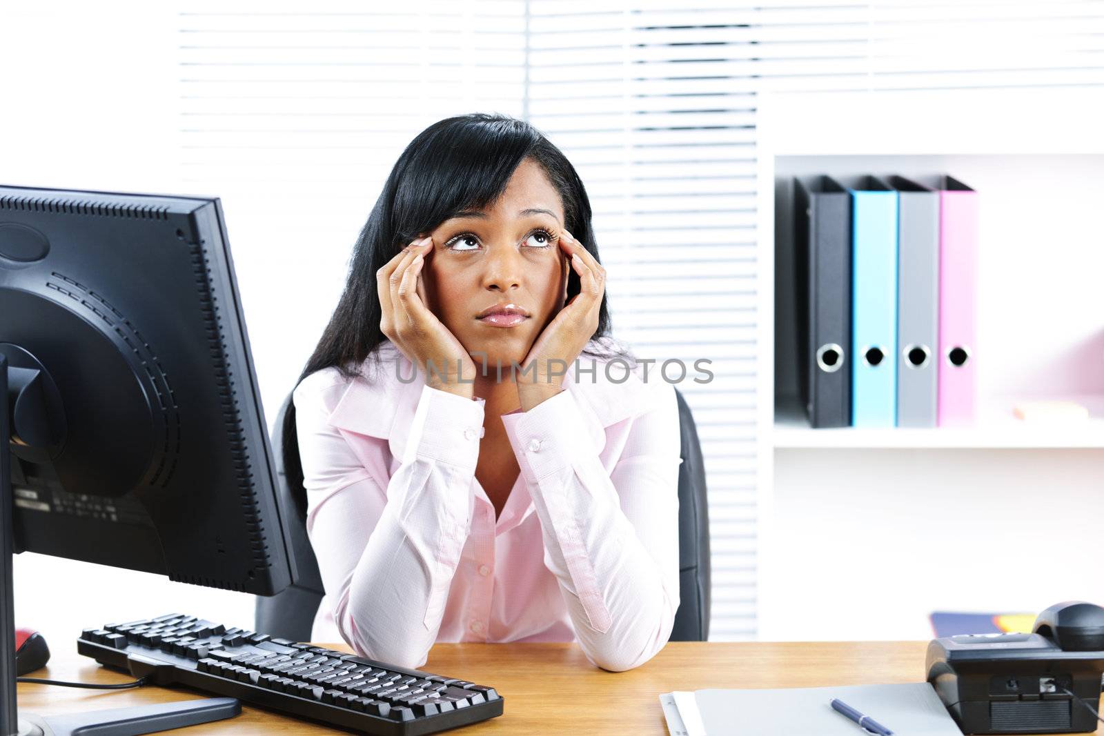 Bored unhappy young black business woman at desk in office
