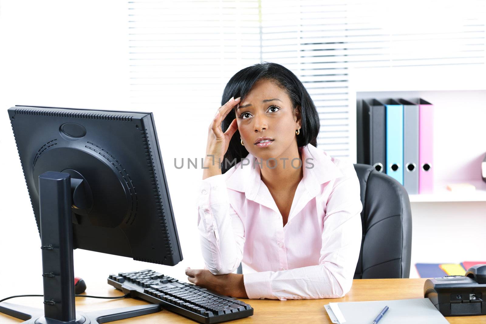 Worried black businesswoman at desk by elenathewise