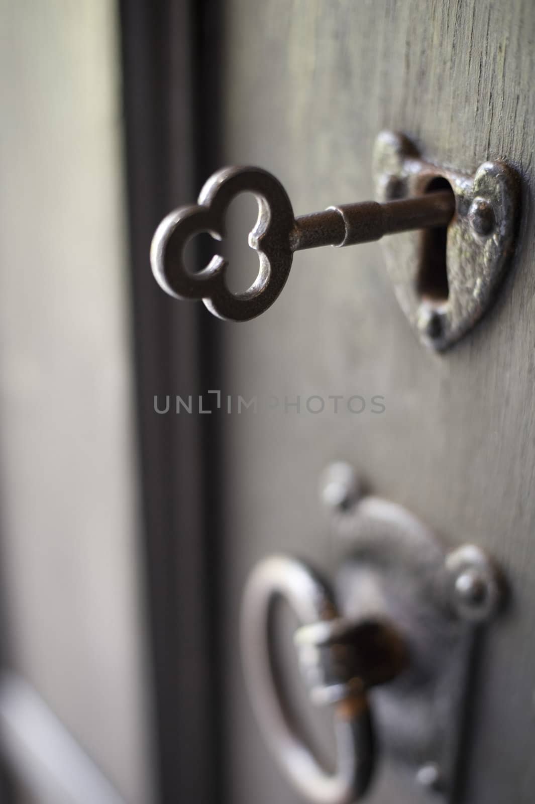 an old door handle and lock with a key in it, pictured with a narrow depth of focus