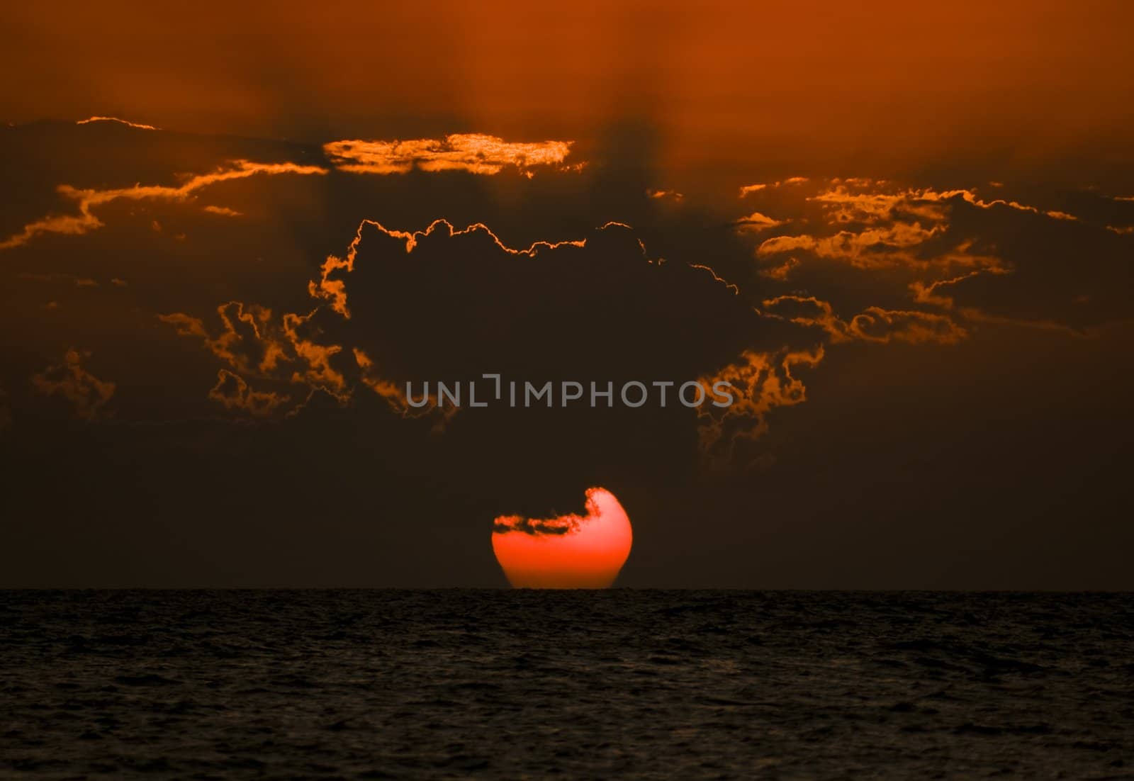Sunset over ocean with dramatic clouds