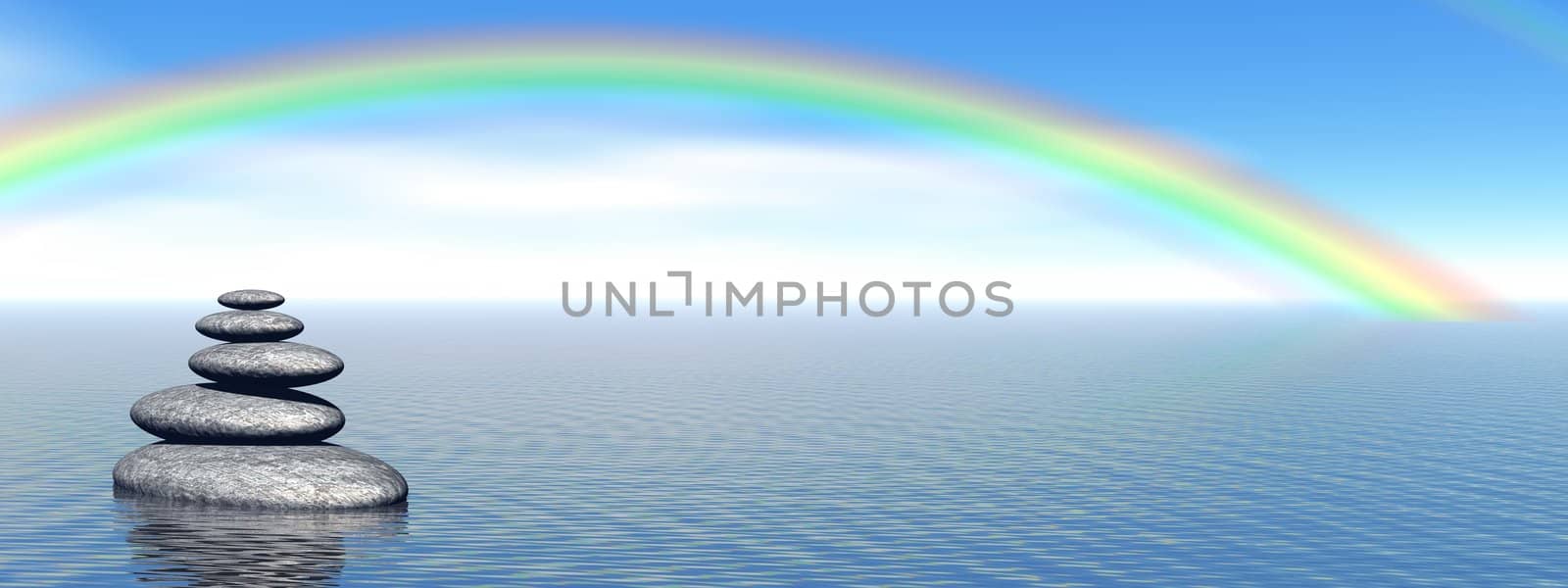 Balanced grey stones in the deep blue ocean with a beautiful rainbow