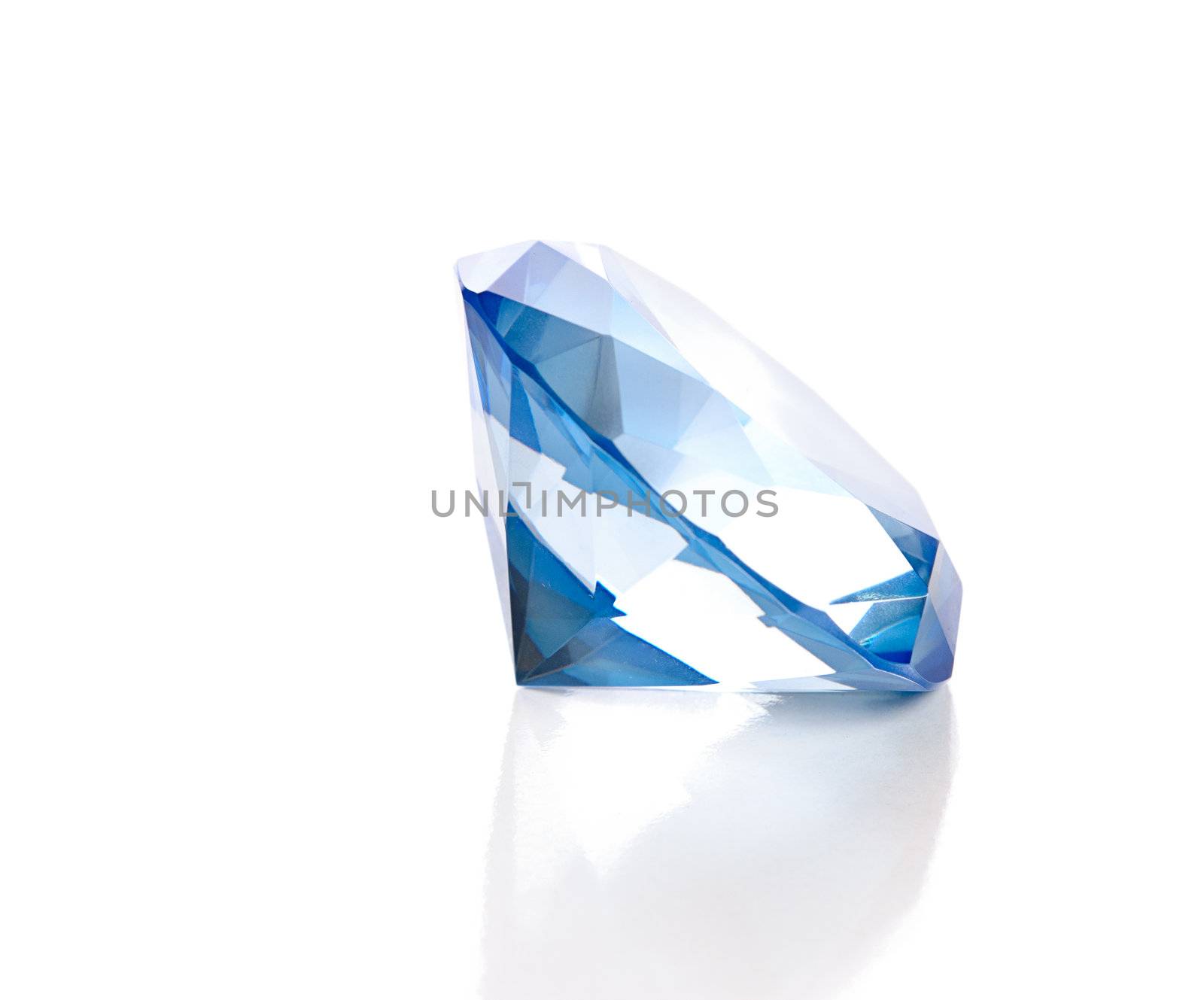 A large fake blue diamond is isolated against a white background with a reflection.