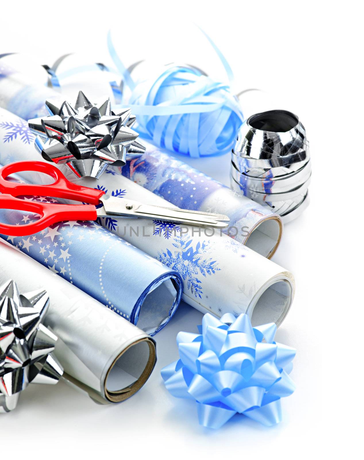 Rolls of Christmas wrapping paper with ribbons, bows and scissors