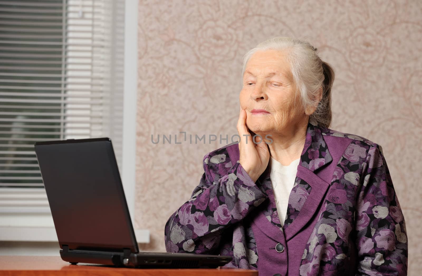 The elderly woman in front of the laptop. A photo in a room