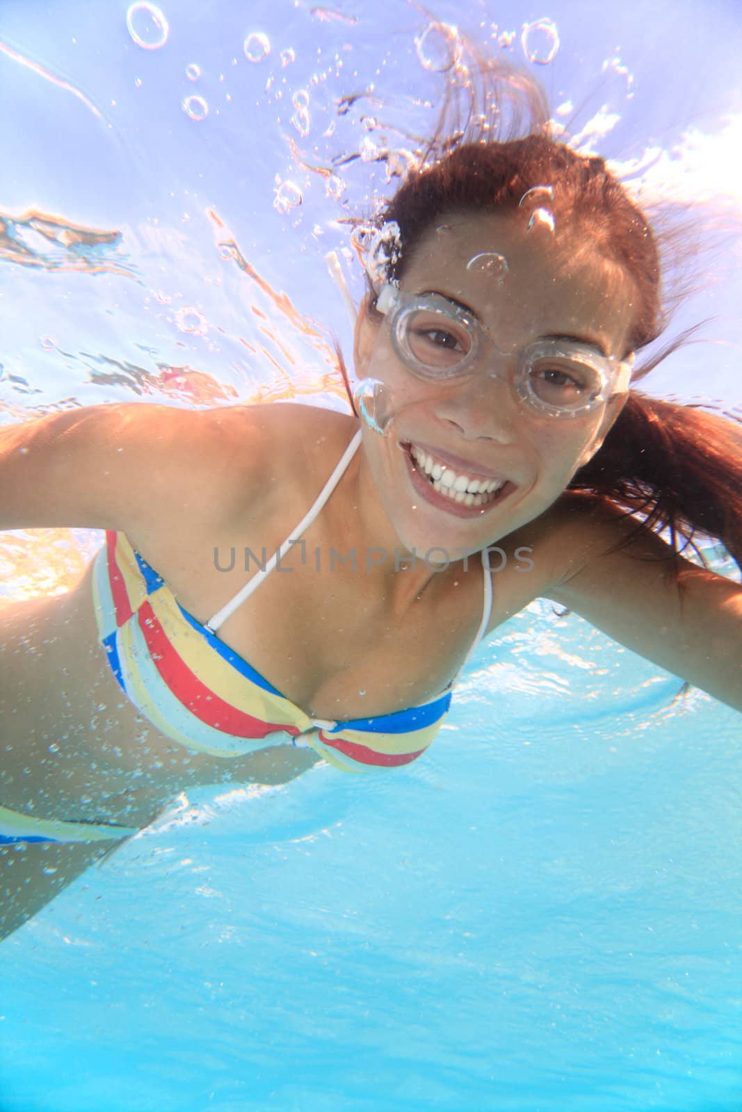 Swimming young woman underwater in pool.