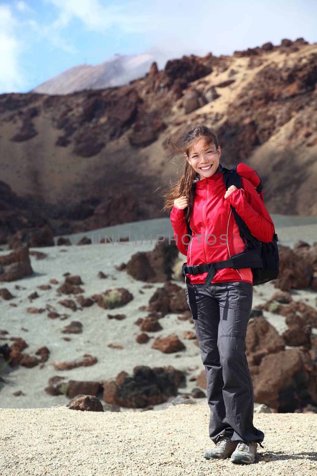 Woman hiking smiling at camera. Beautiful young asian caucasian woman in dramatic volcano landscape on Teide, Tenerife, Canary Islands, Spain.