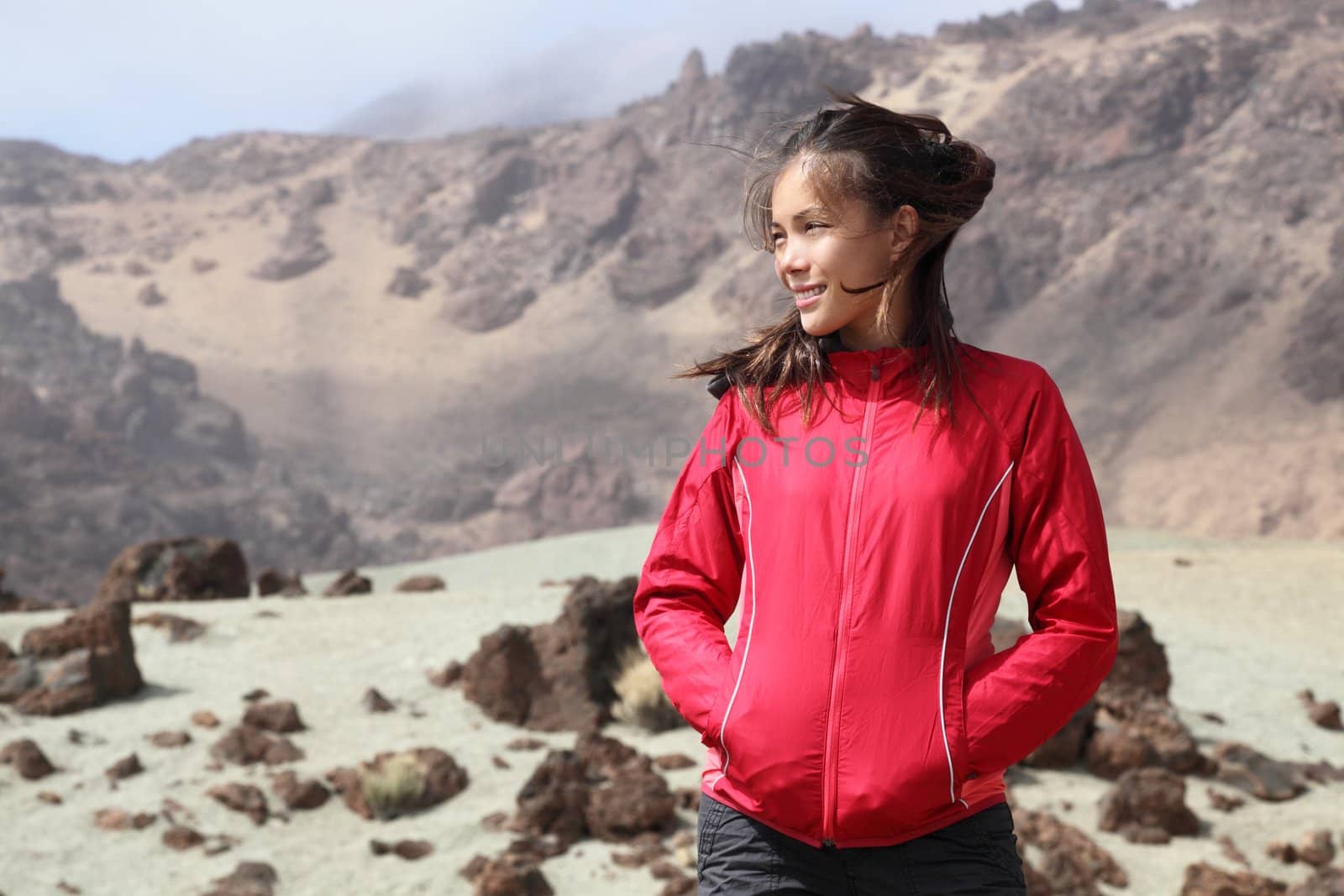 Hiking outdoors person looking at copy space to the side. Asian Caucasian female model. From volcano landscape in Teide National Park, Tenerife, Canary Islands, Spain.