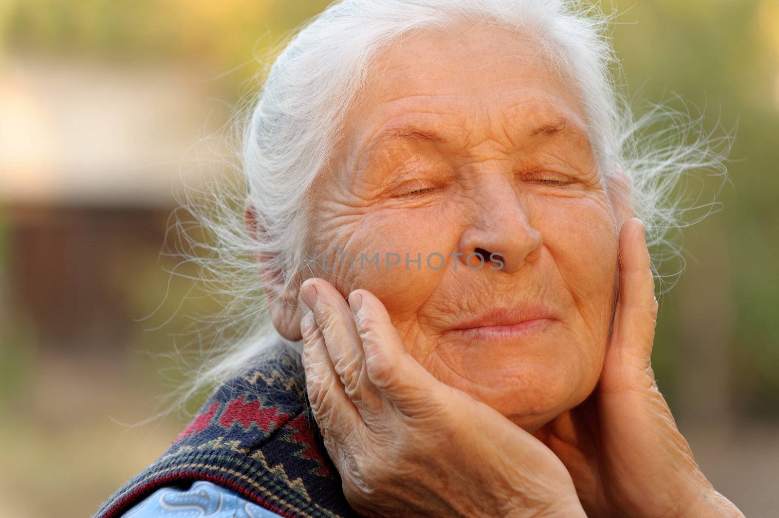 The elderly woman with closed eyes. A photo outdoors