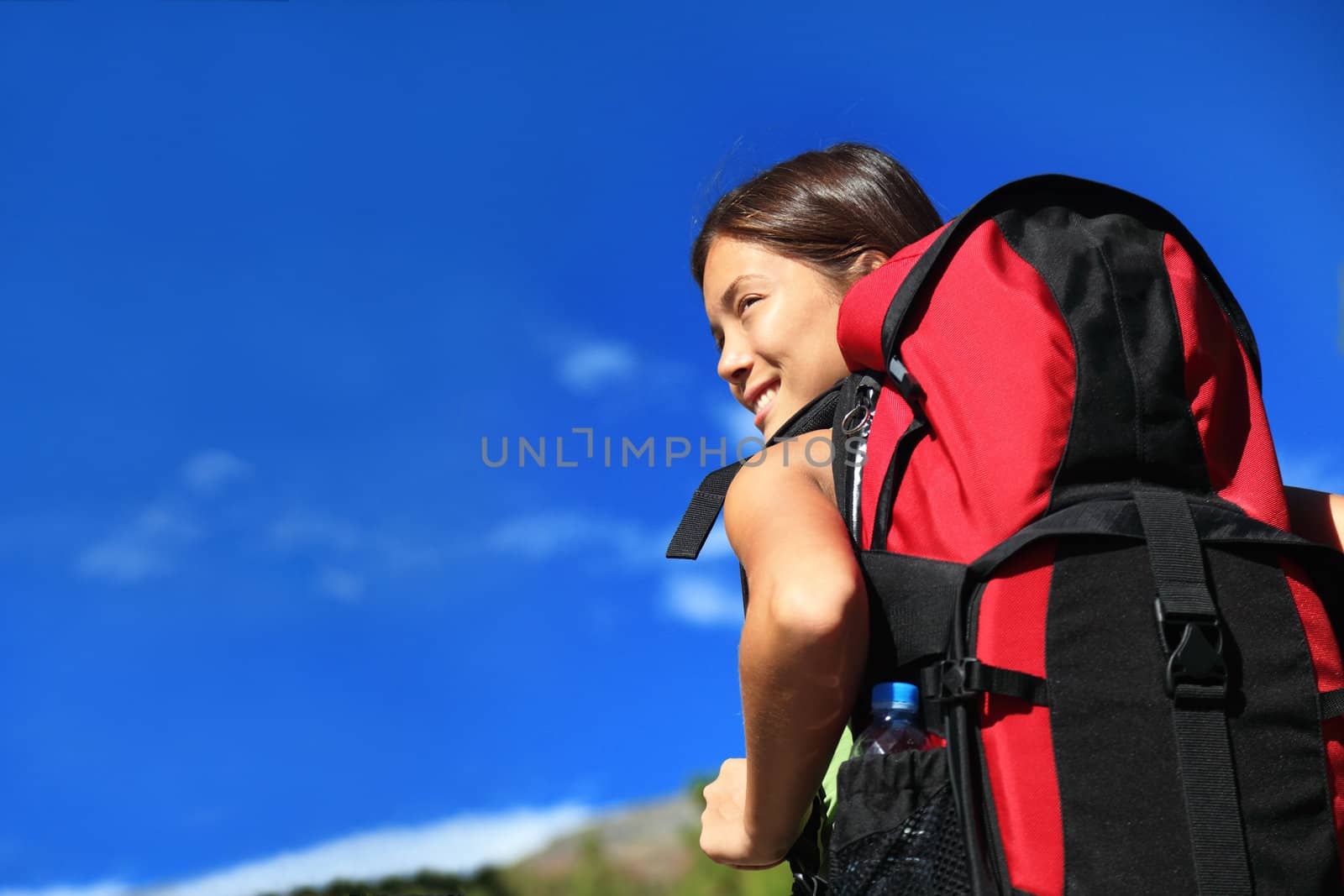 Hiker looking while backpacking / hikiking in nature. Copy space on blue sky. 