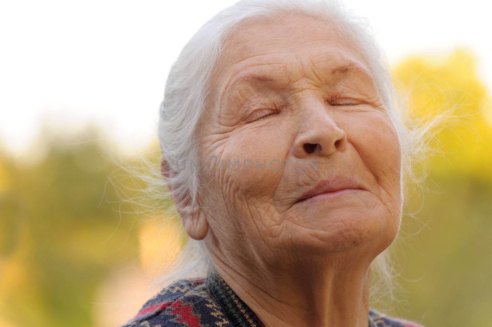 The elderly woman with closed eyes. A photo outdoors