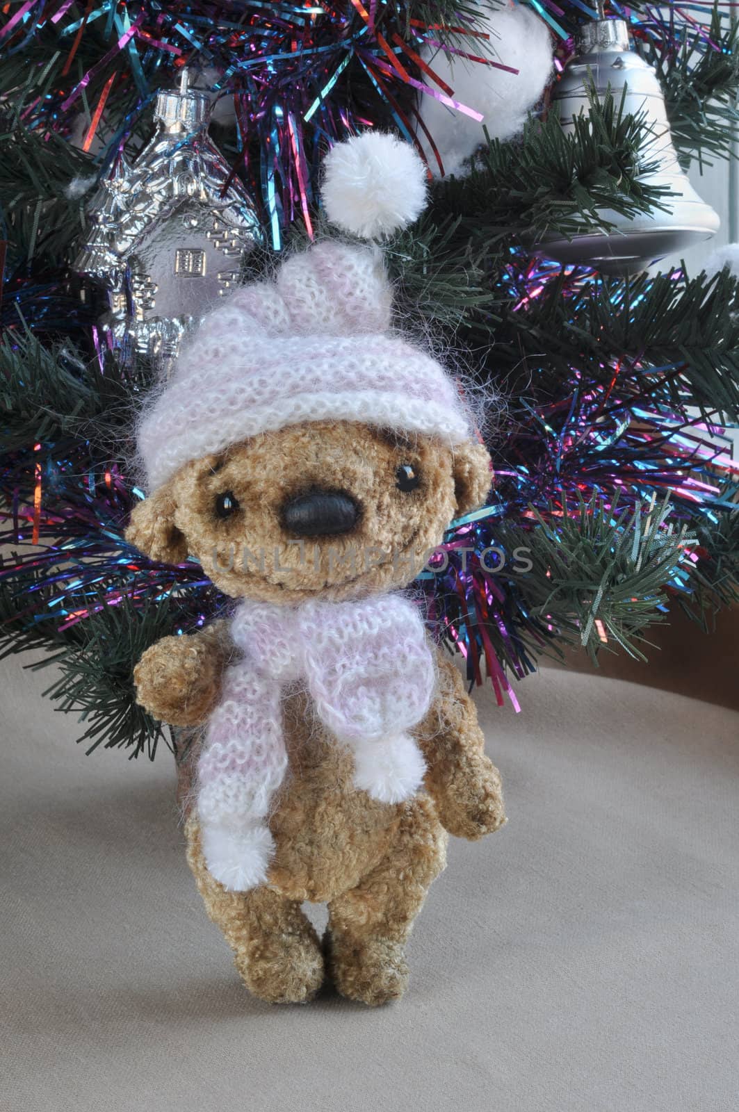 Toy teddy bear in a knitted cap, handmade, under a christmas tree