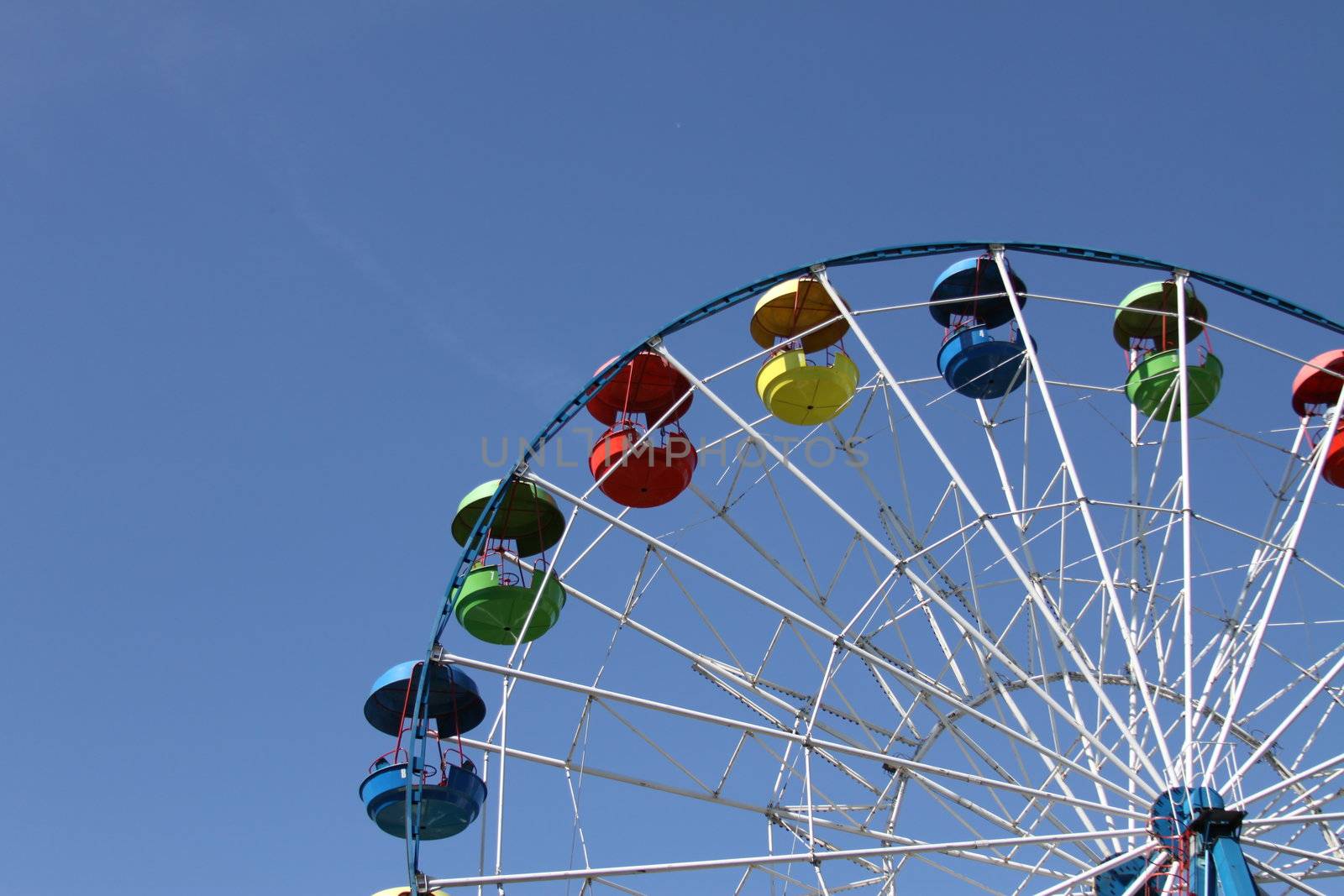 Ferris wheel close up over blue sky.