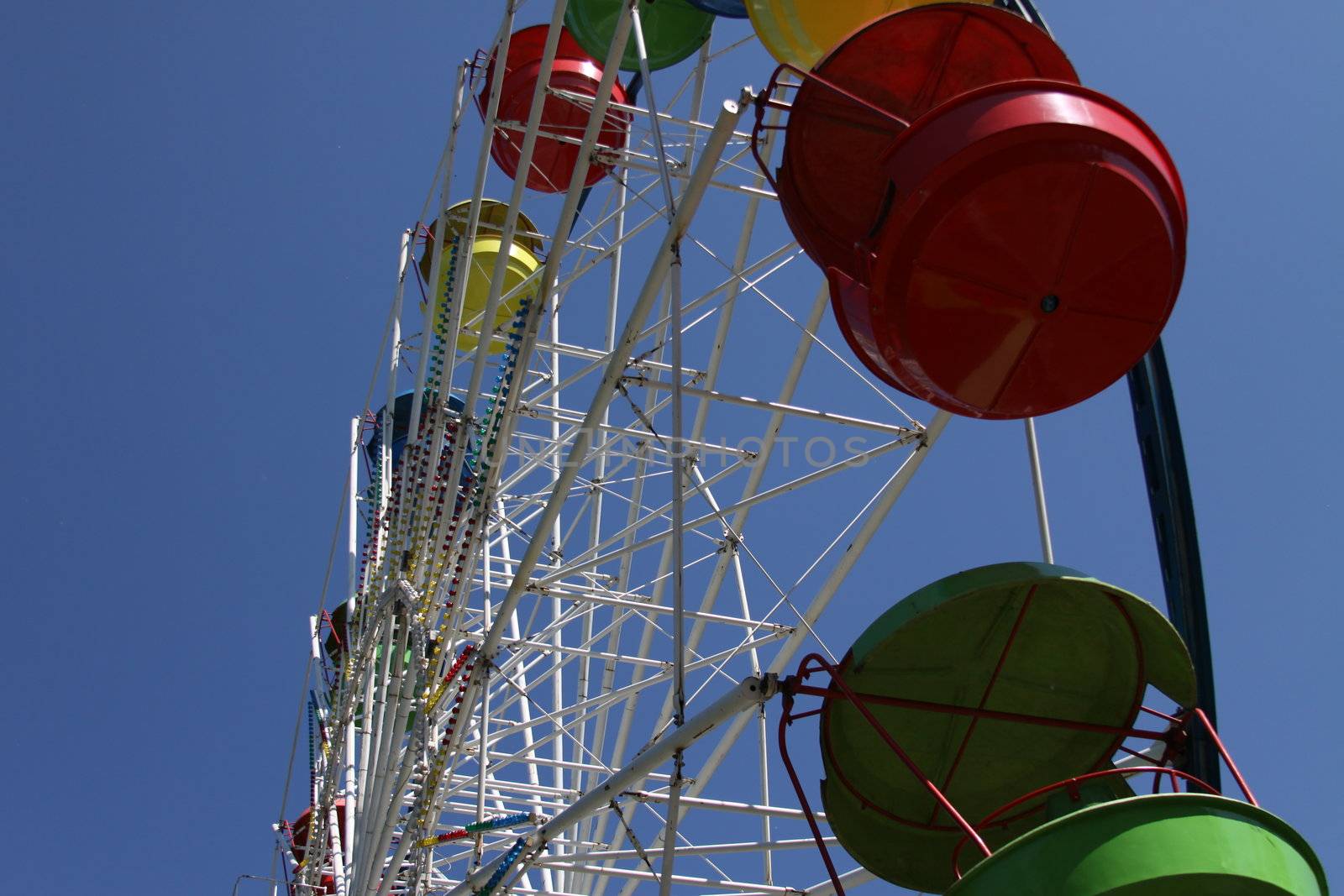 Ferris wheel close up over blue sky.