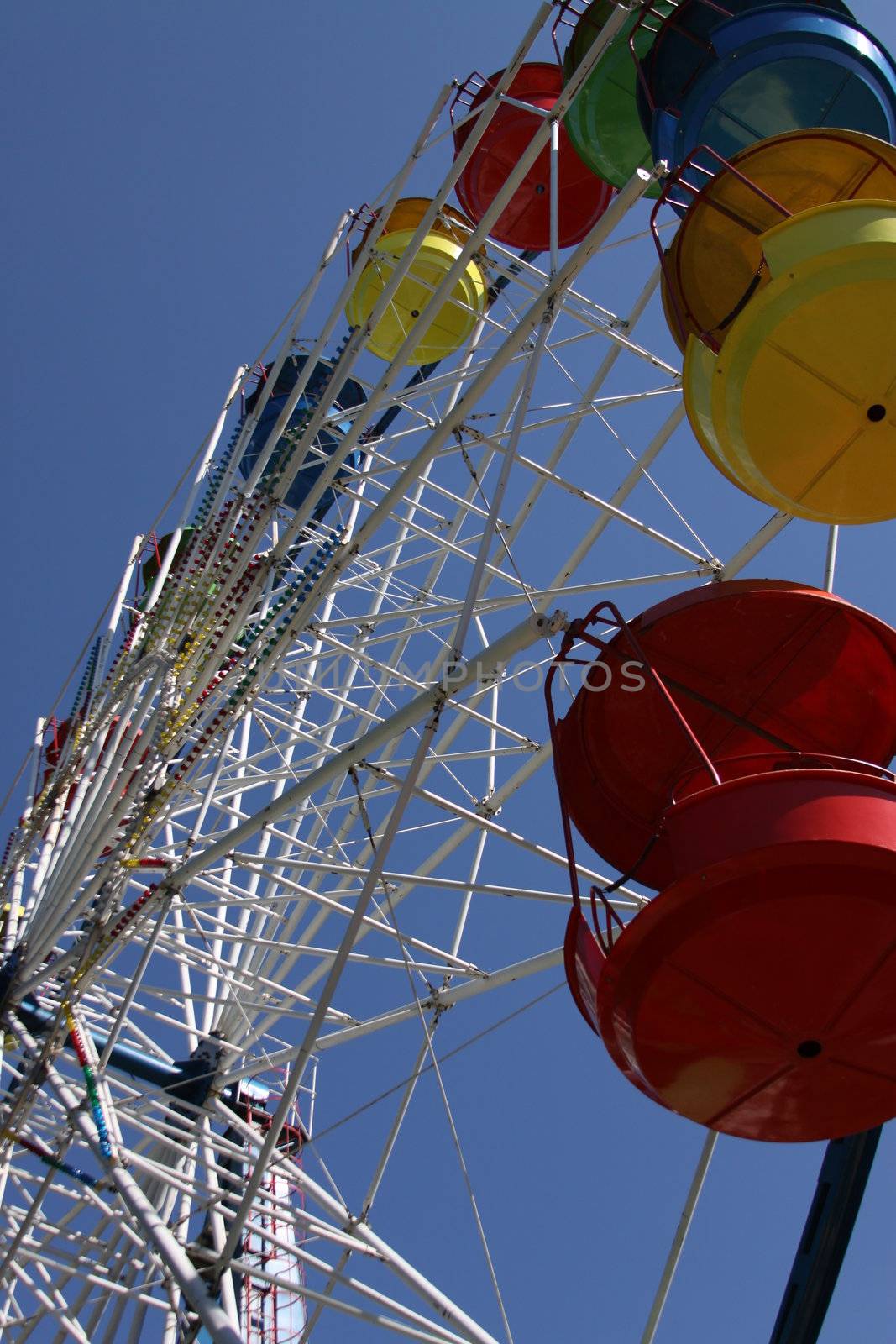 Ferris wheel close up over blue sky.