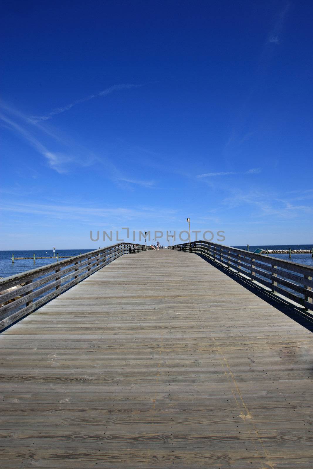 Old wooden pier going into the ocean with a blue sky
