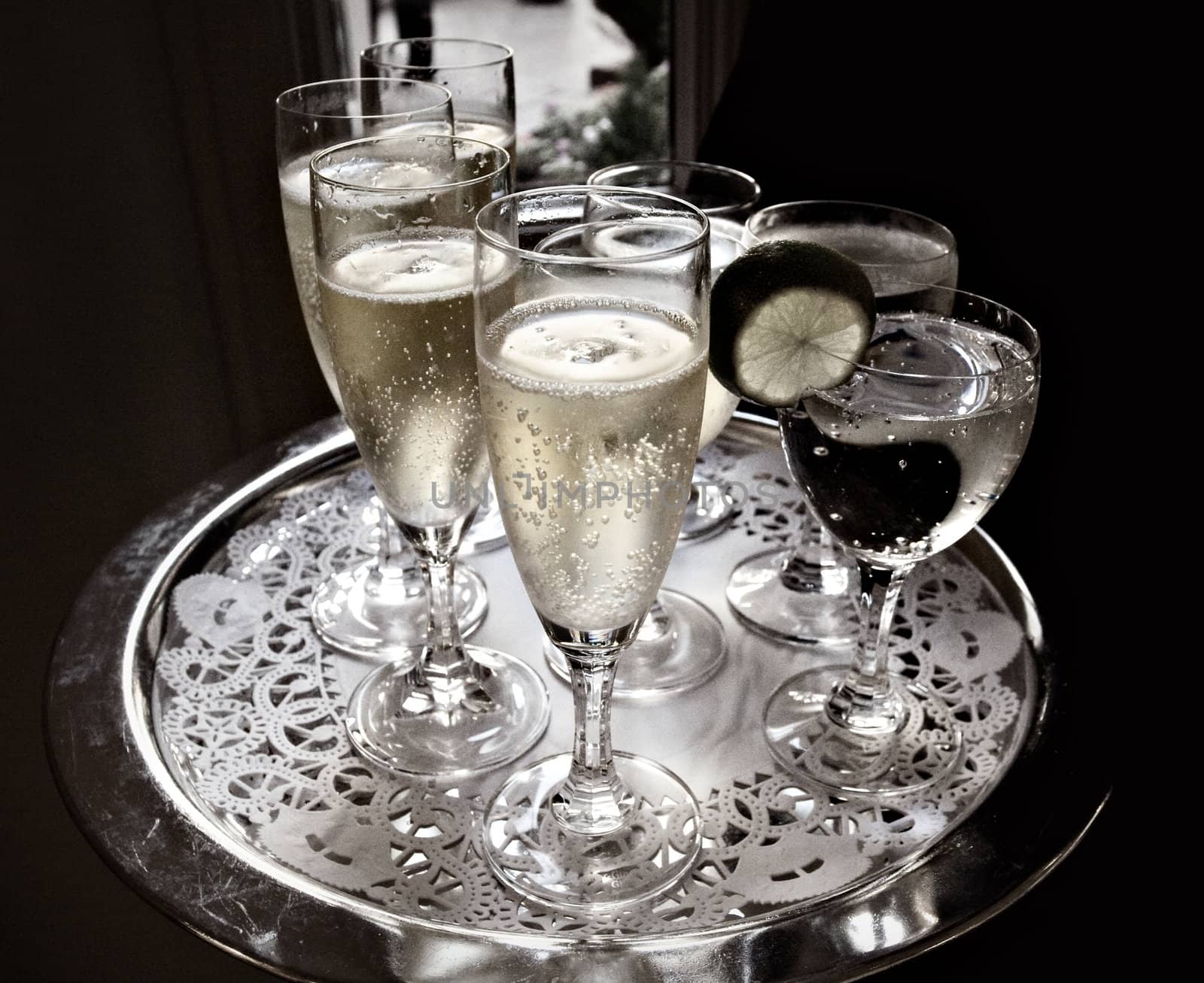 A waiter serves sparkling wine and water on a silver tray