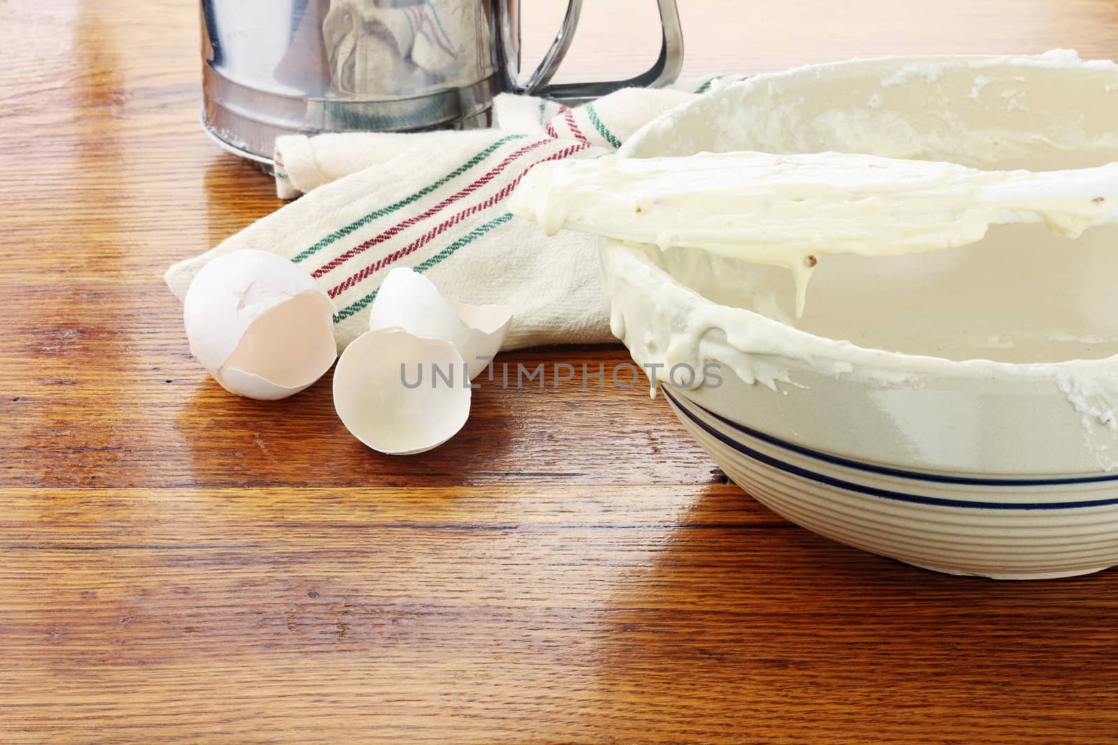 Old fashion mixing bowl with cake batter or pancake batter sitting on a rustic wooden table.