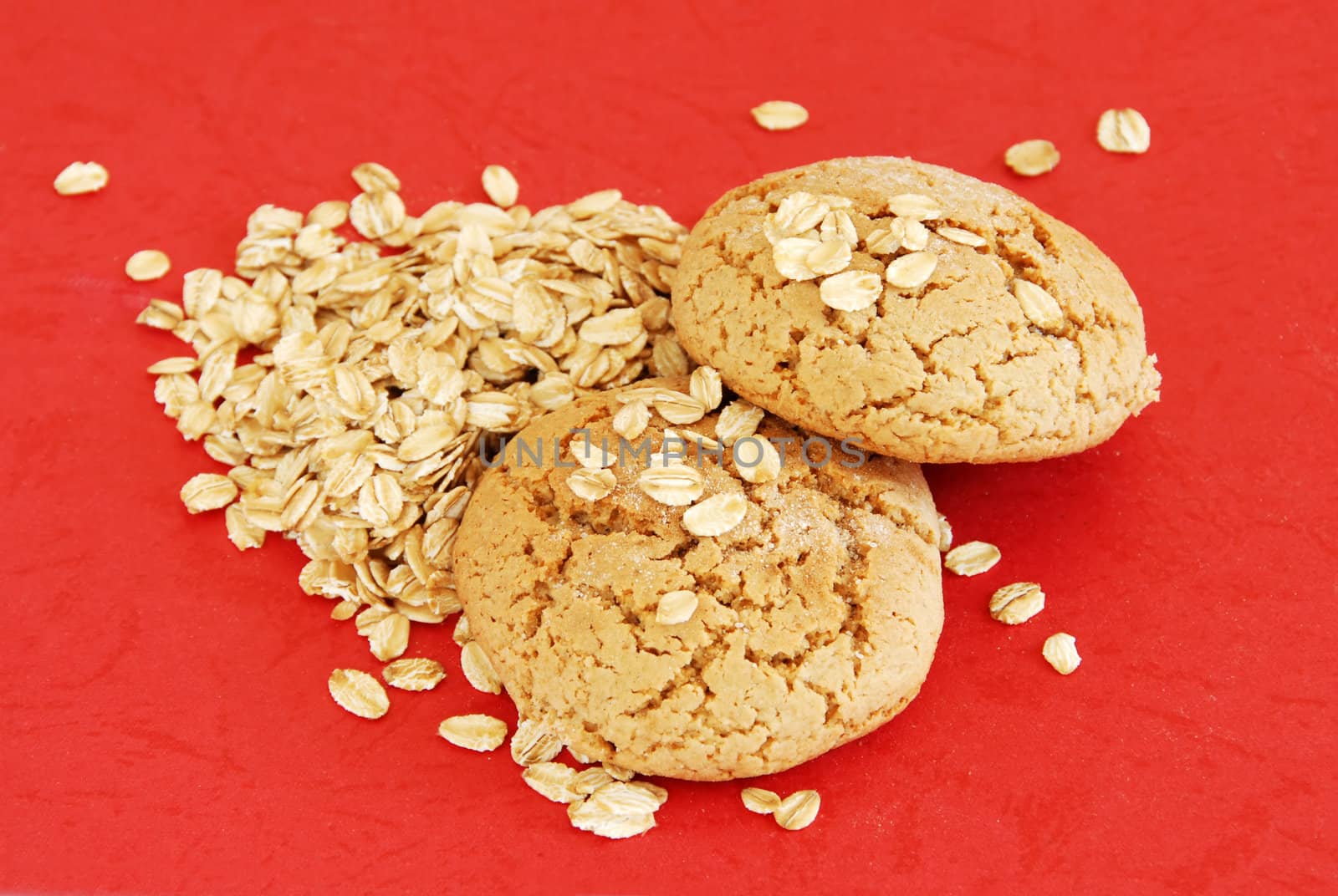 two fresh appetizing oatmeal cookies over red background