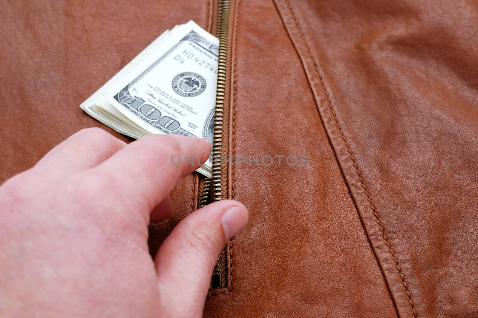 Hand taking dollars from a pocket of leather jacket.