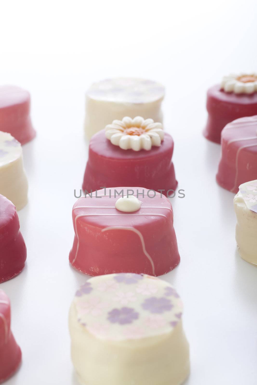 Gourmet pink petits fours image with vertical orientation.