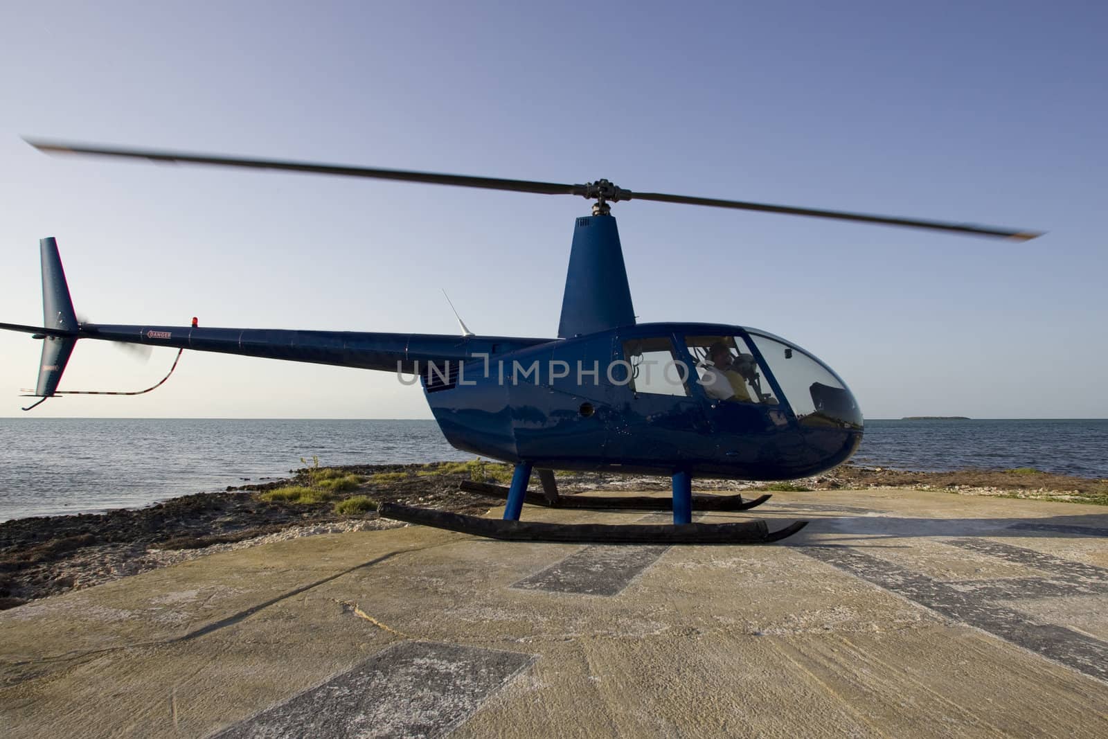 Helicopter Robinson 44 landed on an helipad in front of the ocean