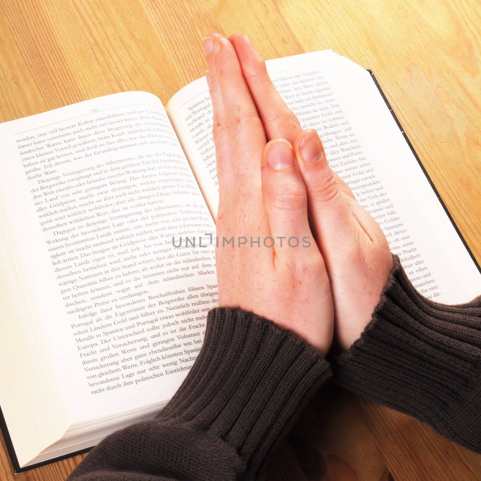 praying hand and book on desk showing religion concept