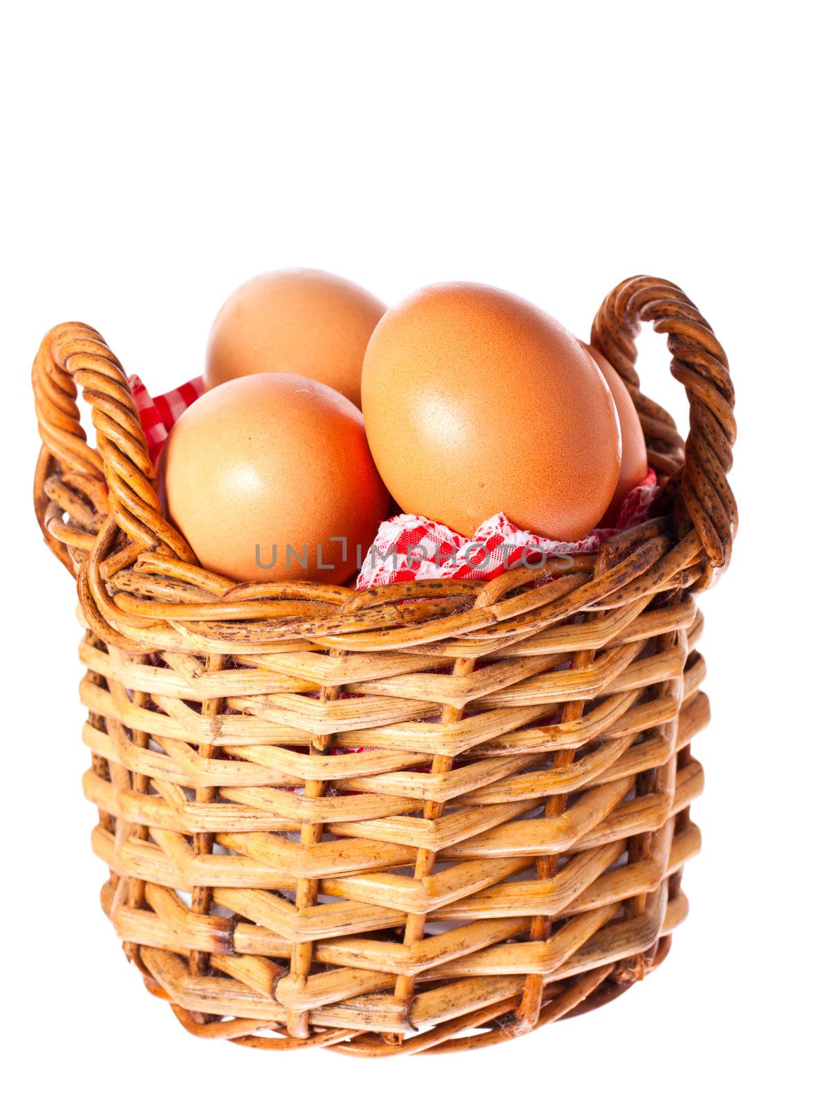 Fresh delicious brown free range chicken eggs in a cane basket with a red checkered cloth. Isolated over white with clipping path.