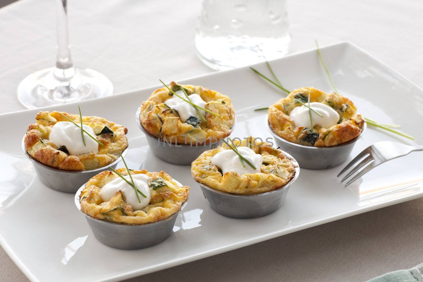 Five quiche appetizers with sour cream and chives.