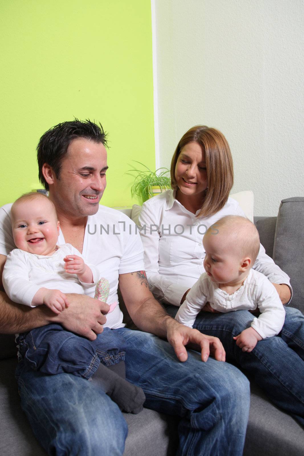 Young families with babies - twins. The parents and the baby laugh friendly and happy.
