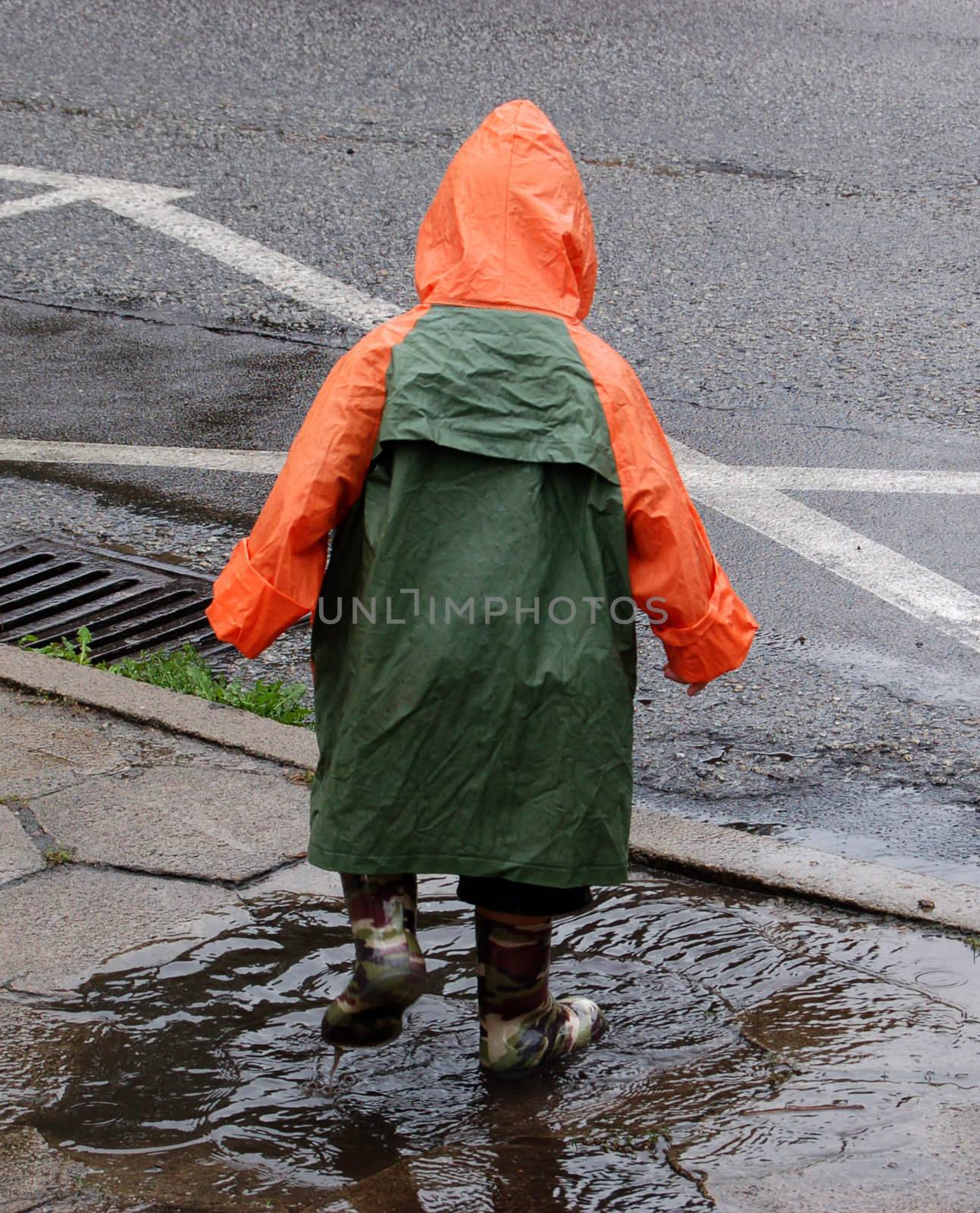 Little kid playing in puddle on a street