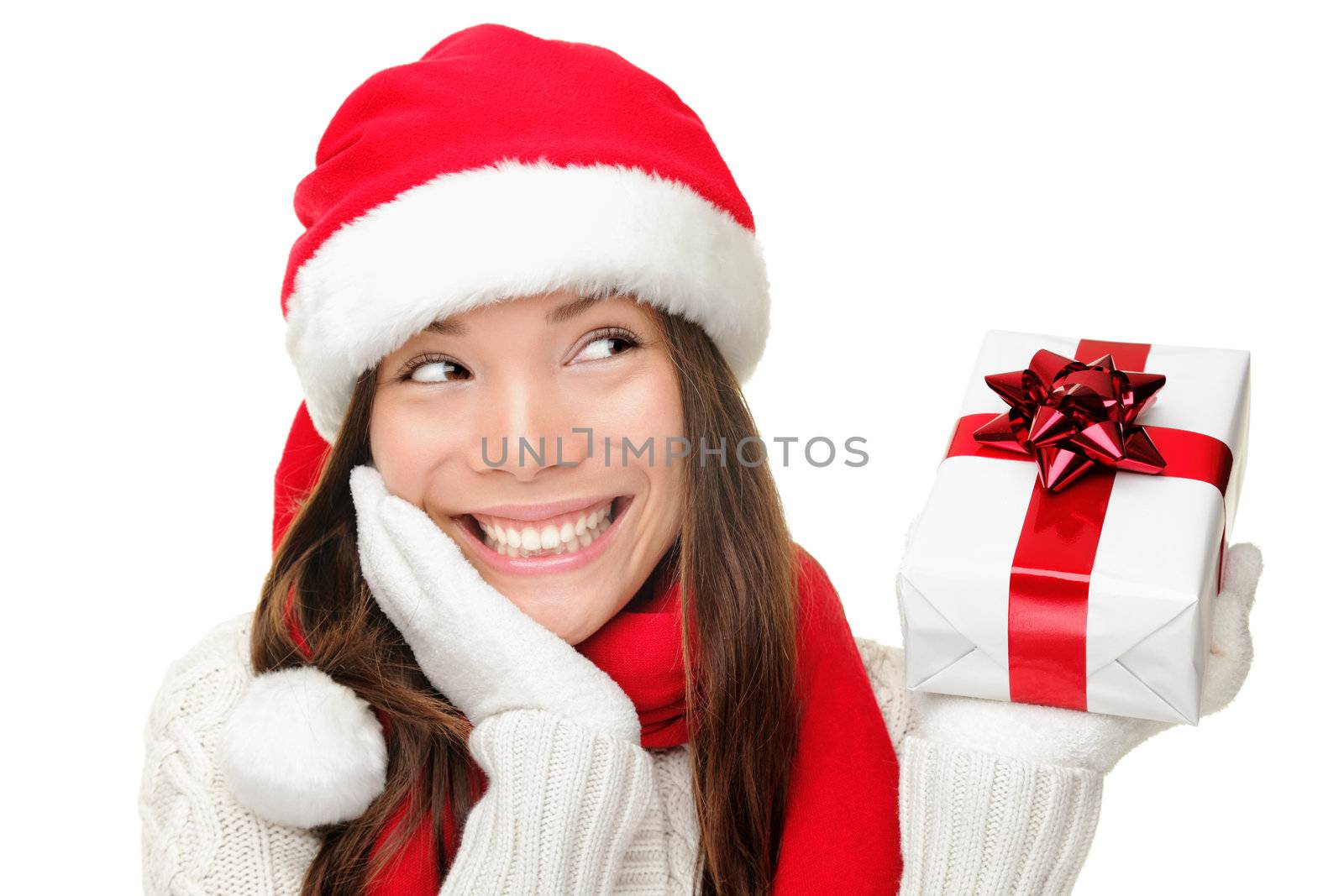 Santa girl holding christmas gift. Young happy woman in santa hat looking sideways showing Christmas present isolated on white background. Beautiful cute young santa woman.