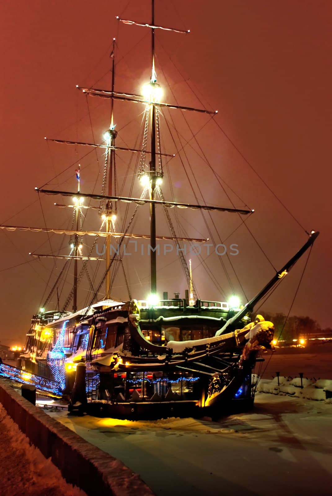 Ancient sailing vessel is at a quay at night