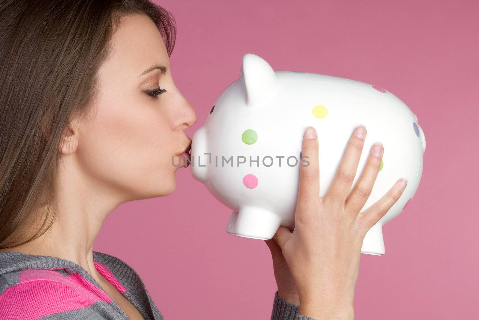 Pretty girl kissing piggy bank