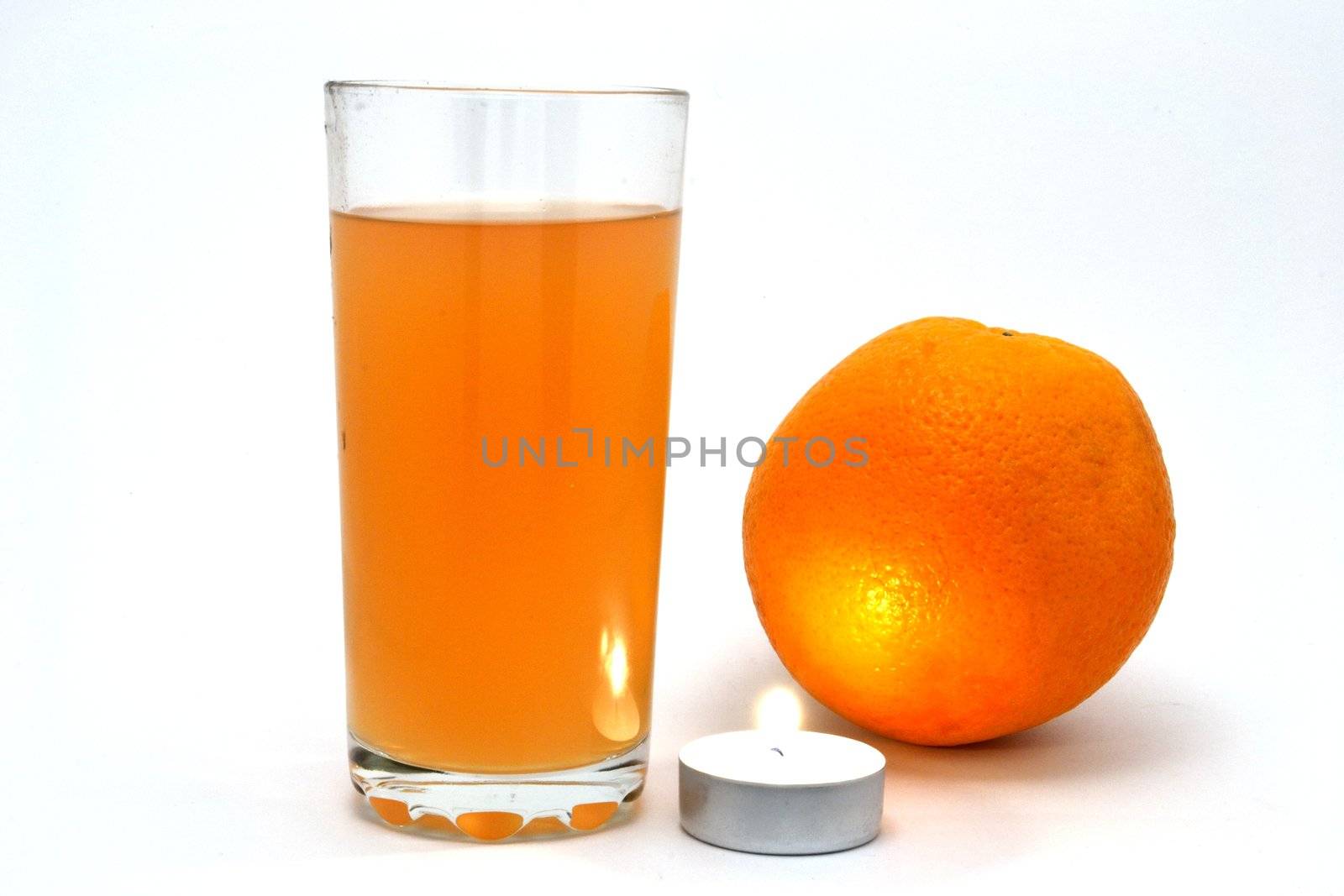 The glass full of juice and the orange over white background