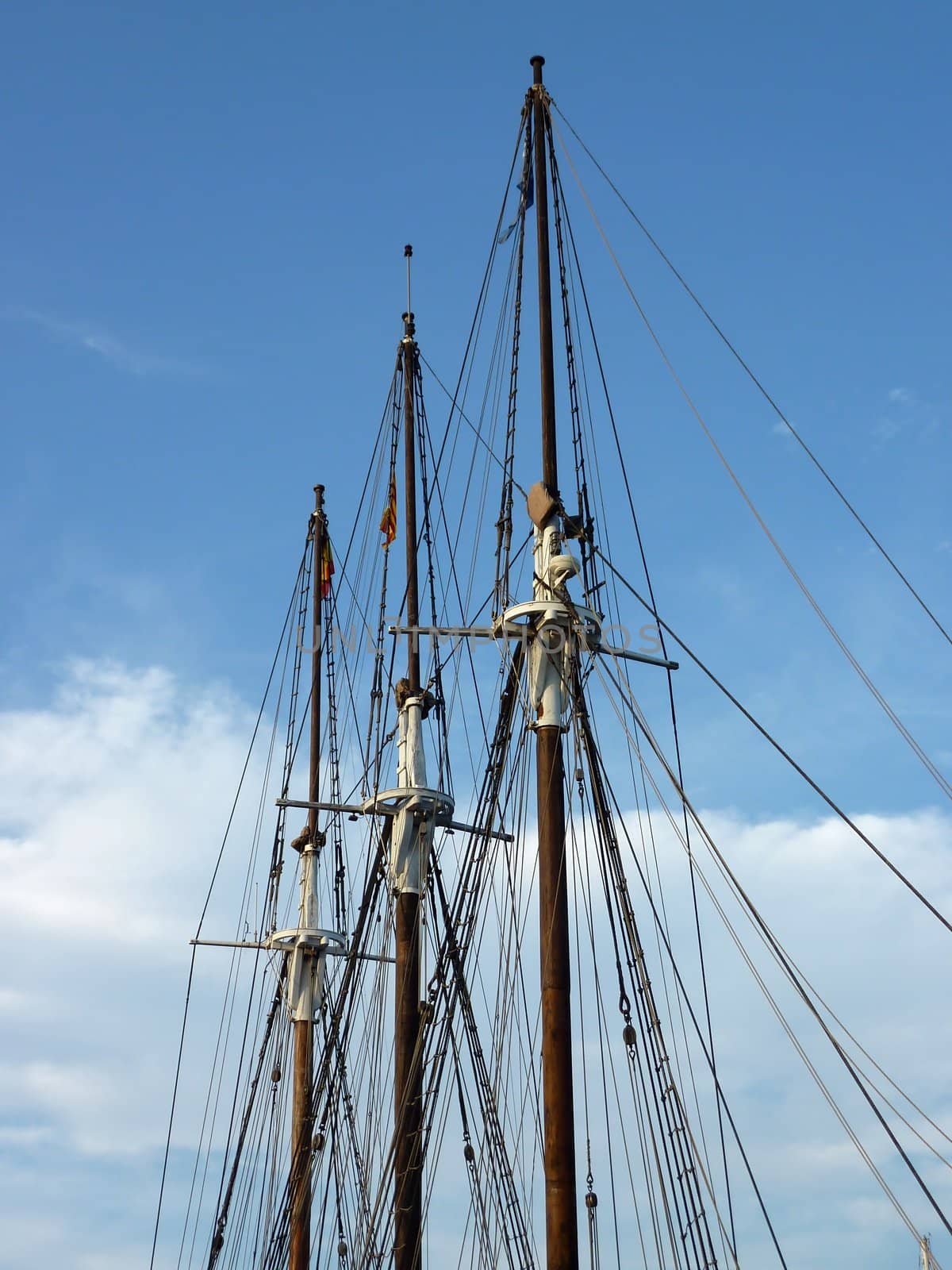 Three masts of a historical boat and coulds and blue sky