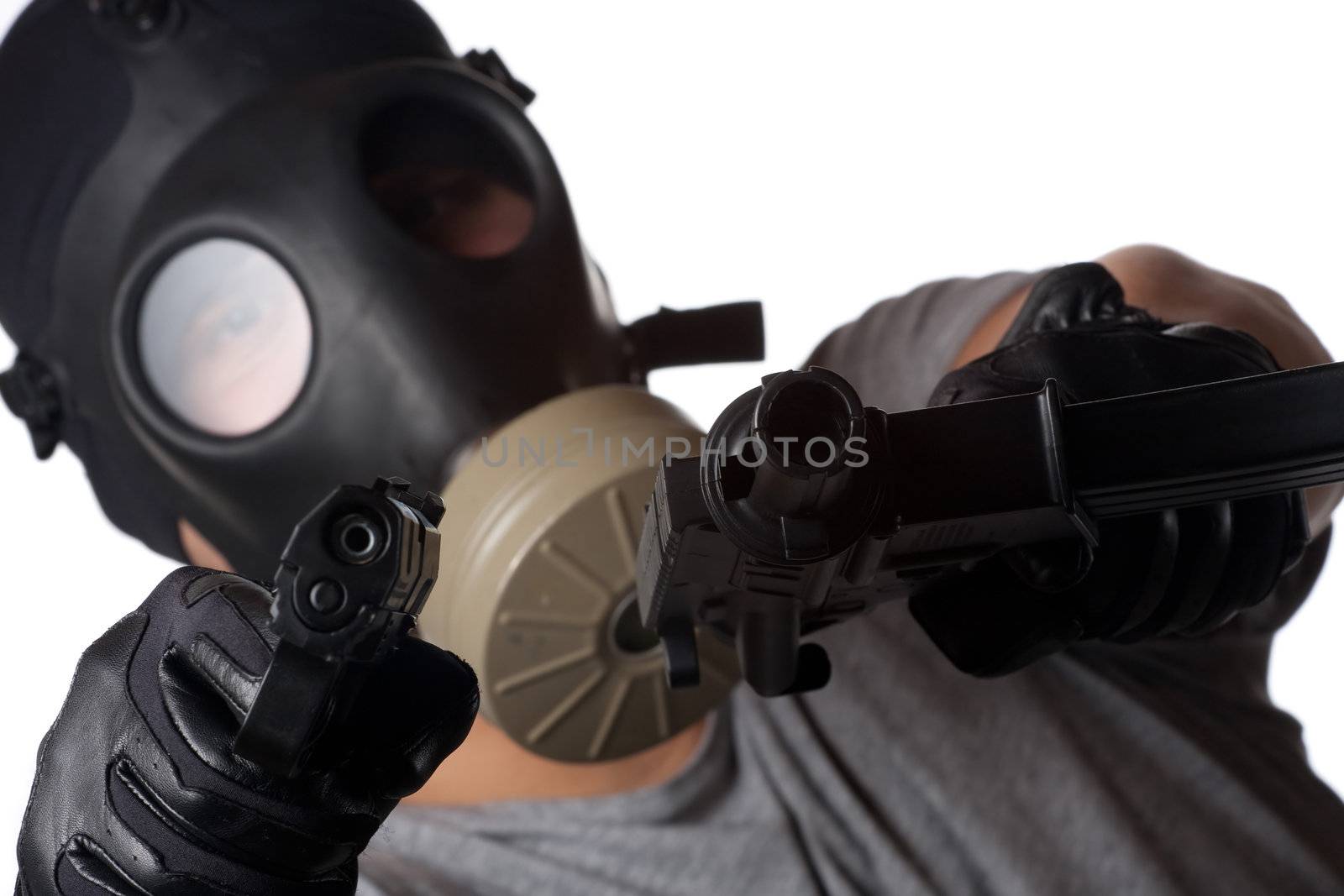 A man wearing a gas mask pointing two guns at the viewer. Shallow depth of field.  Works great for crime or warfare concepts.