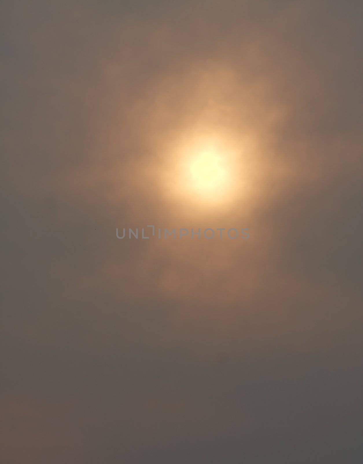 defocused background of pale sun behind clouds