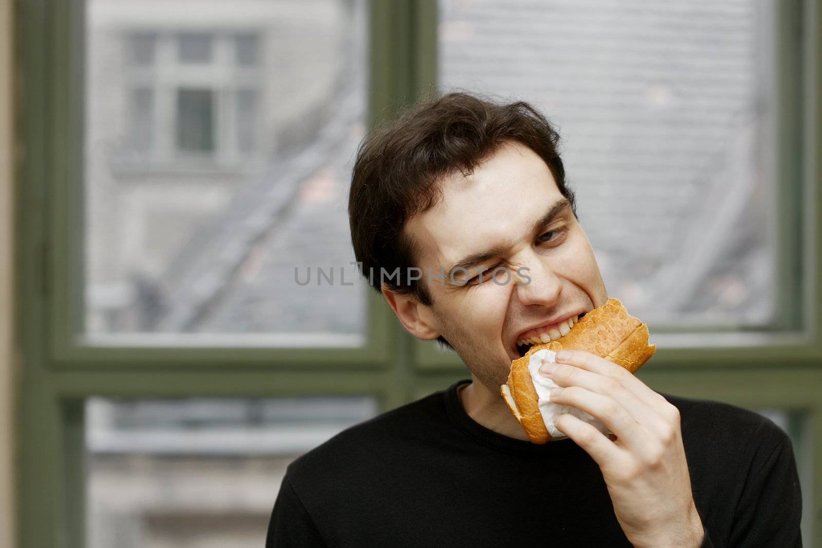 Man eating a sandwich with strange expression